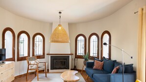 A living room with a fireplace, sofa, armchair, and a hanging light fixture. - Villa 'Ensueño' with Sea View, Wi-Fi and Air Conditioning (Calonge)