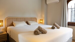 A neatly made bed with rolled towels, a bedside lamp, and an air conditioning unit on the wall. - Villa 'Ensueño' with Sea View, Wi-Fi and Air Conditioning (Calonge)
