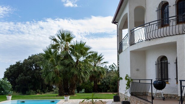 A pool area with lounge chairs, a palm tree, and a building with a balcony. - Villa 'Ensueño' with Sea View, Wi-Fi and Air Conditioning (Calonge)