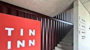 A staircase with a red sign reading "TIN INN" and a wall with vertical wooden slats. - TIN INN Nettetal-Kaldenkirchen (Nettetal)