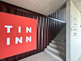 Una escalera con un letrero rojo que dice "TIN INN" y una pared con listones de madera verticales.