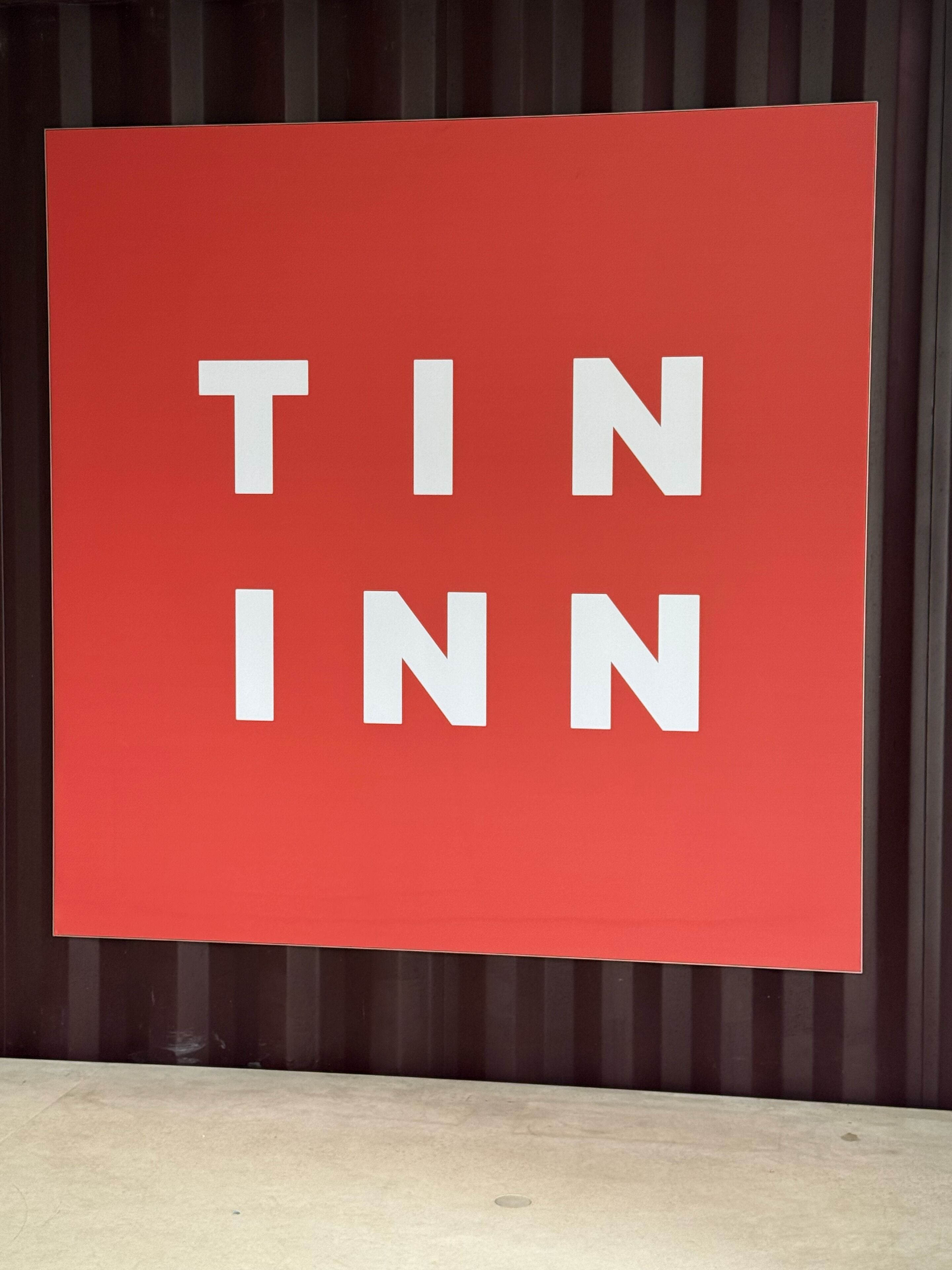 Et rødt skilt med hvide bogstaver, der staver 'TIN INN'.