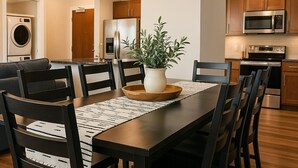 Eine moderne Küche mit Holzschränken, Edelstahlgeräten und einem Essbereich mit einem Holztisch und Stühlen.