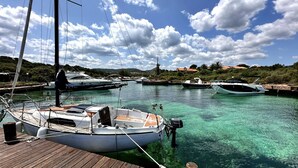 En småbåtshamn med flera båtar förtöjda, en träbrygga och en klarblå himmel med moln.