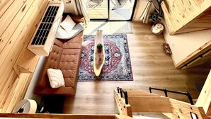 L’intérieur d’un chalet en bois, avec un ventilateur de plafond, un canapé, un tapis et un coin repas.