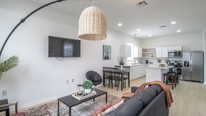A modern kitchen with white cabinets, a stainless steel refrigerator, and a microwave. - Contemporary 3BR Home by New Orleans Culture (New Orleans)