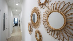 A hallway with multiple mirrors on the wall, a door, and a carpeted floor. - Contemporary 3BR Home by New Orleans Culture (New Orleans)