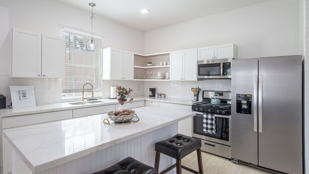 A modern kitchen with white cabinetry, a stainless steel refrigerator, a microwave, and a gas stove. - Contemporary 3BR Home by New Orleans Culture (New Orleans)