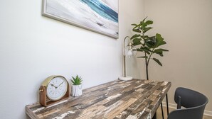 A wooden desk with a clock, a potted plant, and a lamp. - Contemporary 3BR Home by New Orleans Culture (New Orleans)