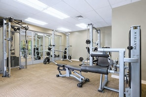 Une salle de sport équipée de matériel de musculation, de miroirs et dotée d’un plancher en bois.