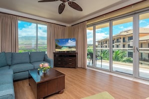 A living room with a sofa, coffee table, TV, and large sliding glass doors to a balcony.