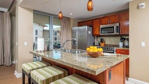 A modern kitchen with a central island, stainless steel appliances, and a view to the outside.