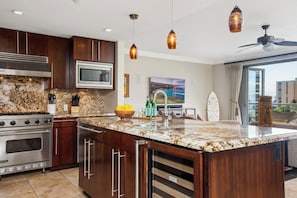 A modern kitchen with a large island, stainless steel appliances, and pendant lighting.