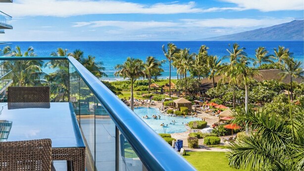 Un complexe hôtelier doté d’une piscine, de palmiers et offrant une vue sur l’océan.