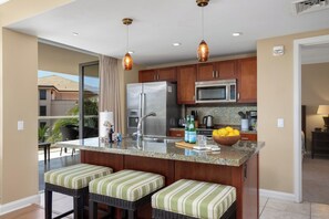 A modern kitchen with a central island, stainless steel appliances, and a view to the outside.