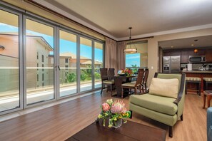 A spacious living room with a large sliding glass door, a dining area with a table and chairs, and a kitchen area with modern appliances.