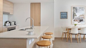 Una cocina moderna con una isla central, una zona de comedor con mesa y sillas, y un cuadro enmarcado en la pared.