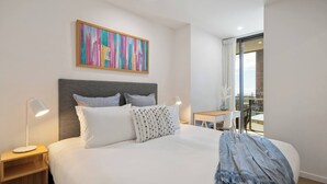 Una habitación de hotel moderna con una cama grande, un escritorio y un balcón con vistas.