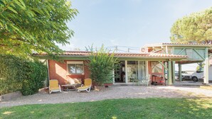 Una casa con patio, muebles de exterior y un vehículo estacionado afuera.