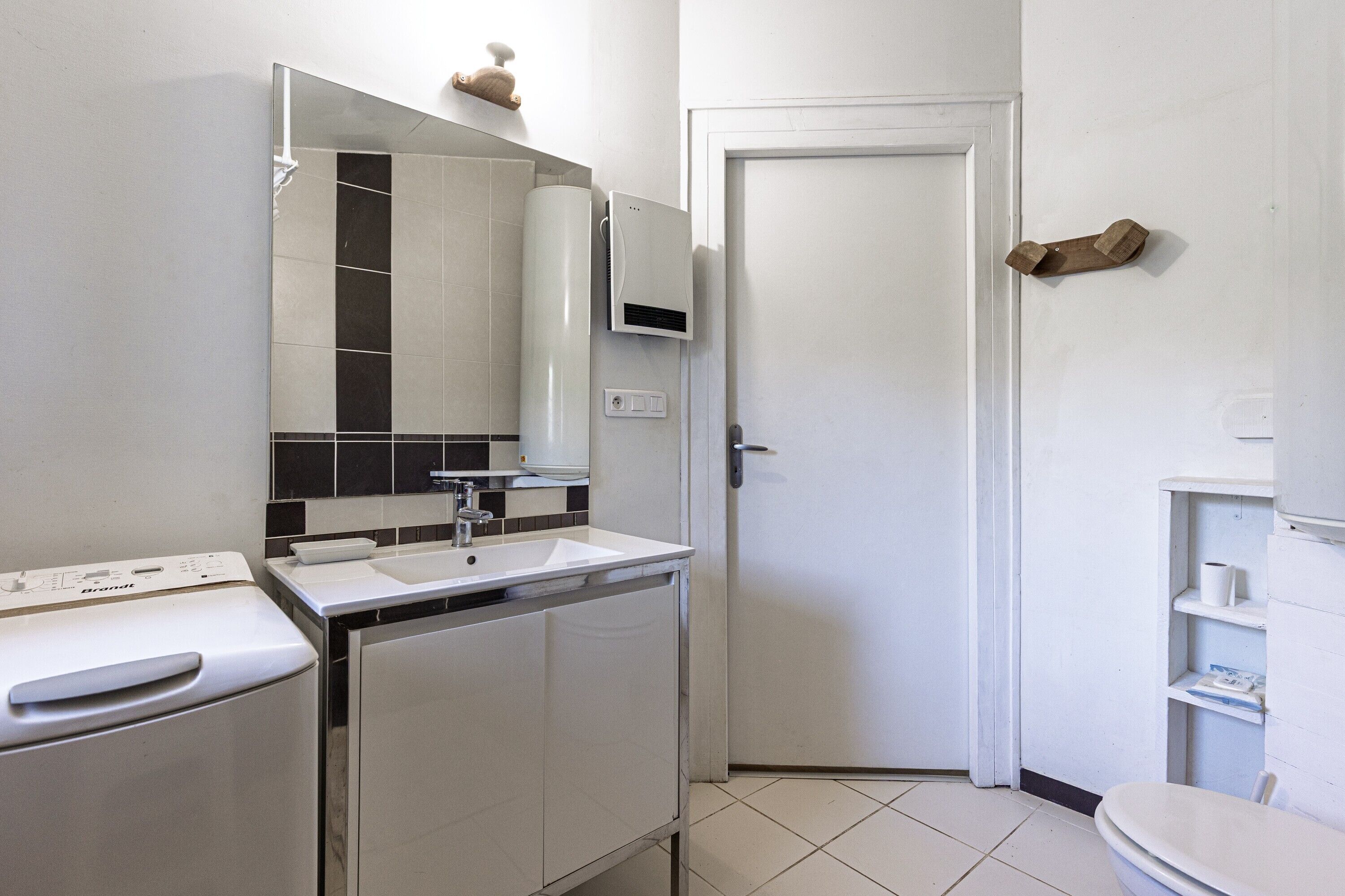 Une salle de bain moderne avec un lavabo blanc, un miroir et des toilettes.