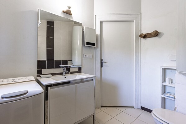 A modern bathroom with a white sink, mirror, and a toilet.