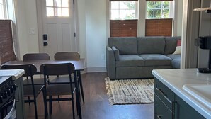 A kitchen with a dining table and chairs, a gray sofa, and a kitchen island. - Cozy Tiny House in Scottsburg (Scottsburg)