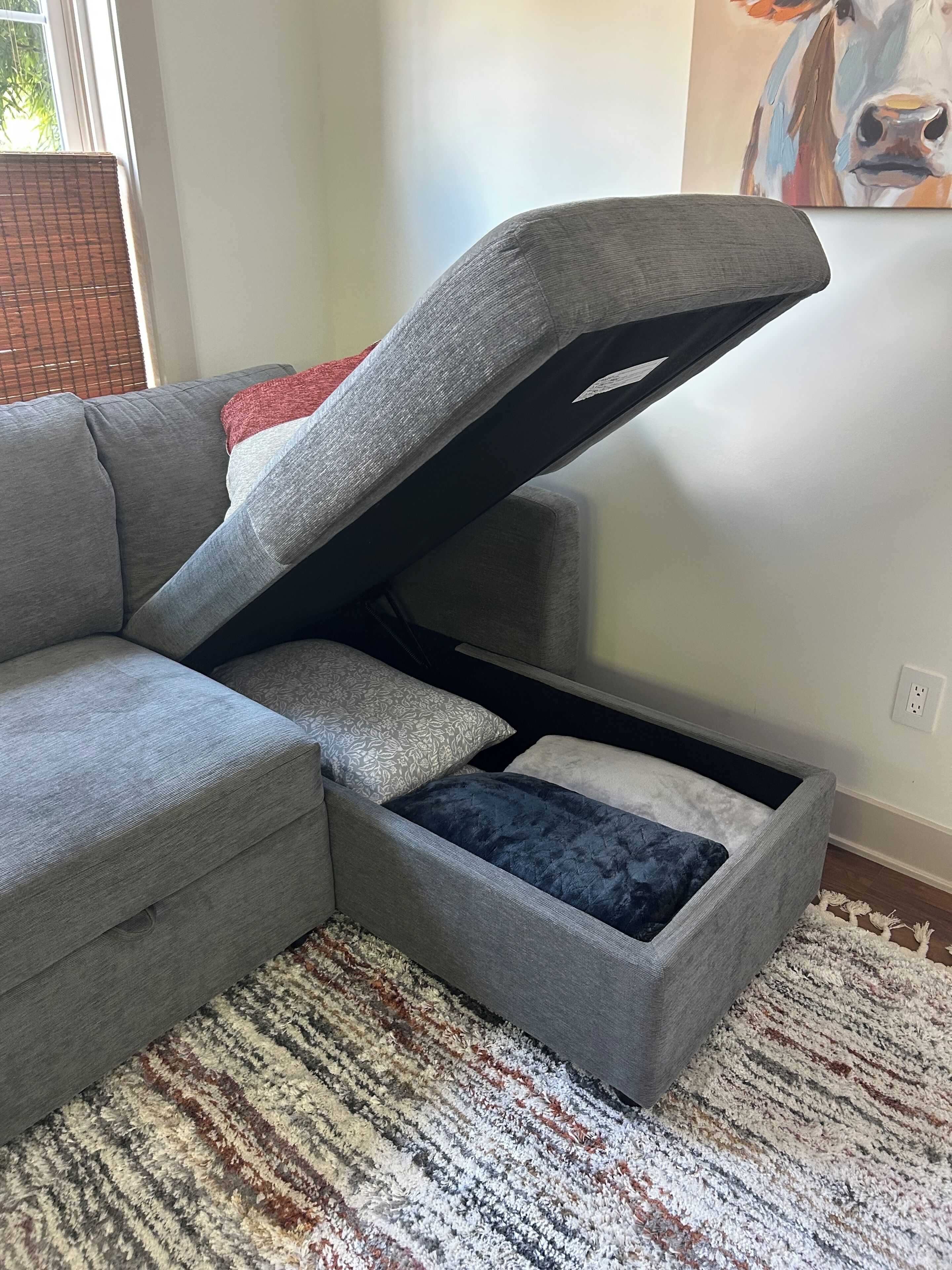 Ein graues Ecksofa mit Stauraum darunter.