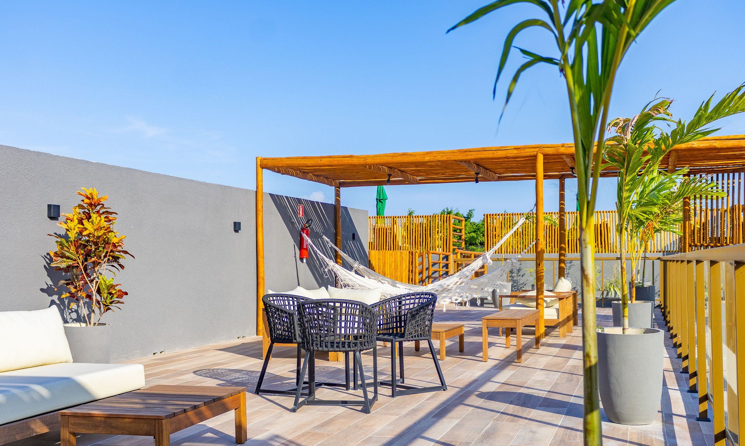 An outdoor patio area with a wooden table and chairs, a hammock, and a potted plant.