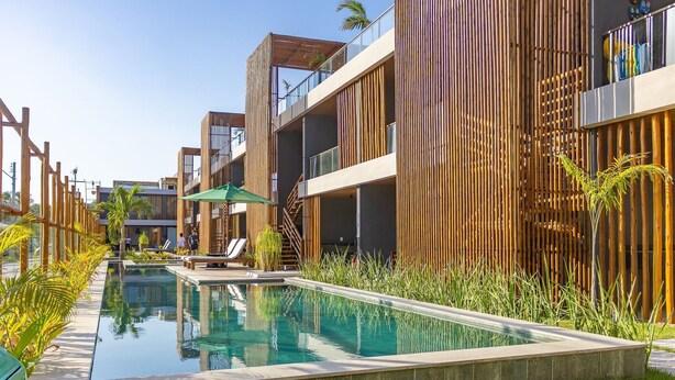 A modern hotel with a pool, wooden slatted walls, and outdoor seating. - TMH - Essence Condominium in Porto de Pedras/al (Porto de Pedras)