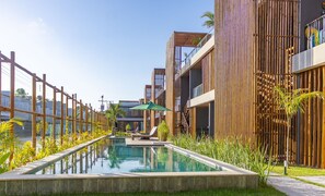 Un espace piscine moderne avec une piscine à eau claire, des chaises longues et une clôture en bambou.