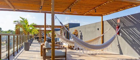 An outdoor patio with wooden furniture, a hammock, and a fire extinguisher.