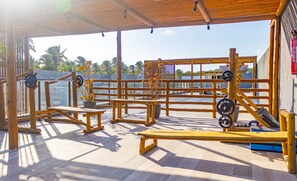 Un espace de remise en forme extérieur abrité, équipé de matériel d’exercice, notamment des bancs, une barre de traction et des stations d’haltérophilie.