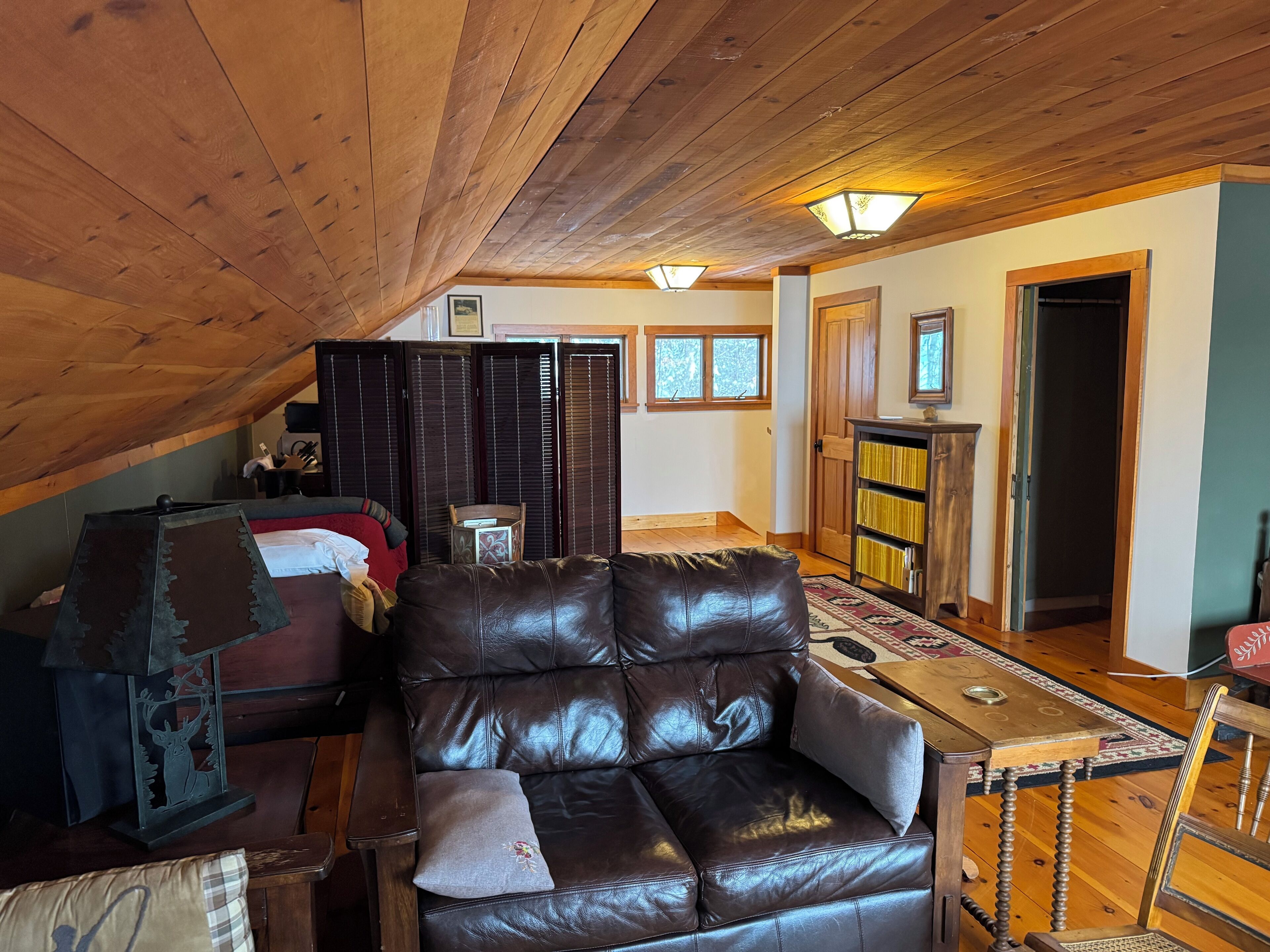 Ein gemütliches Dachzimmer mit Ledersofa, Holztisch und Bücherregal.