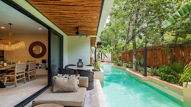 A poolside area with a wooden ceiling, outdoor seating, and lush greenery. - •| Condo Boutique Swim Up in Tulum P/6 • Naaj Tun• (Tulum)