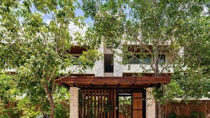 A modern house with a stone facade, a wooden pergola, and lush greenery. - •| Condo Boutique Swim Up in Tulum P/6 • Naaj Tun• (Tulum)