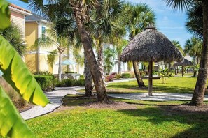 A resort with palm trees, a thatched umbrella, and a pathway. - Kick back at Bikinis & Margaritas, your tropical escape just minutes from Disney (Kissimmee)