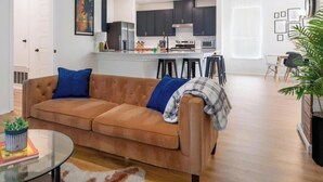Uma sala de estar com um sofá, uma mesa de centro de vidro e um tapete.