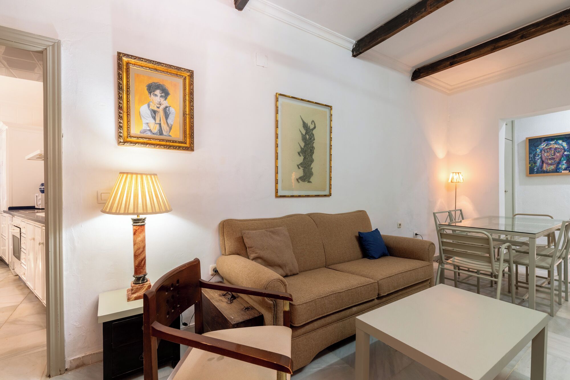 A living room with a sofa, a table, a lamp, and framed artwork on the walls.
