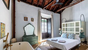 A bedroom with a bed, a dresser, a mirror, a bathtub, and a wardrobe.