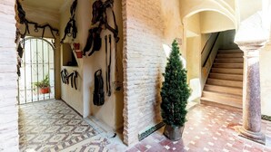 A hallway with a tiled floor, a staircase, and a small potted plant.