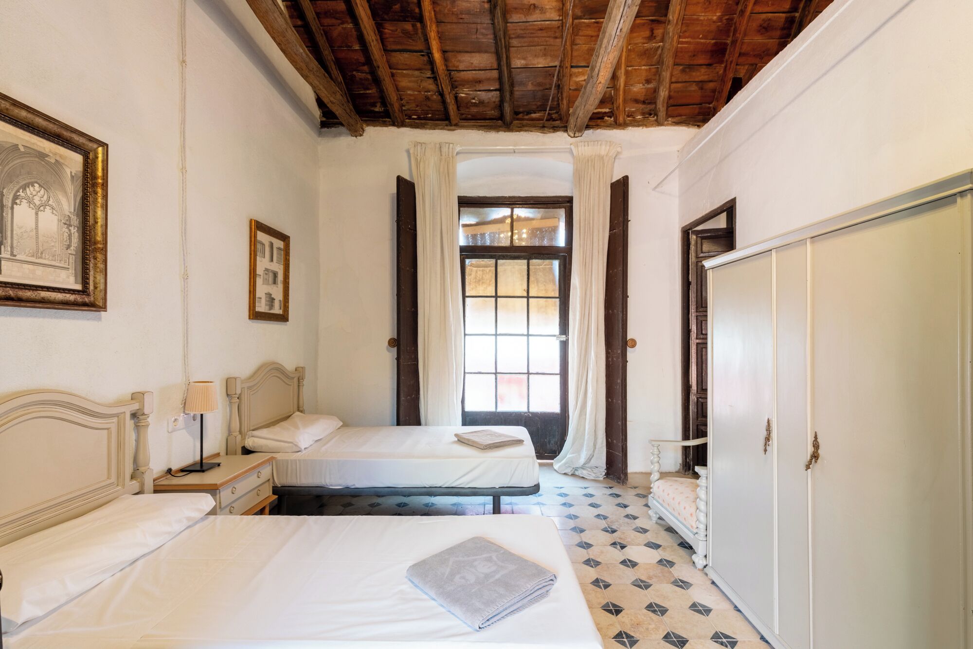 Habitación con dos camas, un armario y una ventana con cortinas.