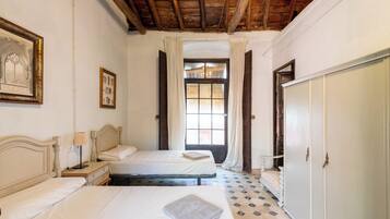 Habitación con dos camas, un armario y una ventana con cortinas.