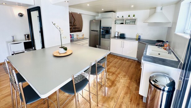 A modern kitchen with a central island, stainless steel appliances, and a wooden floor.