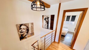 A staircase with wooden steps and metal railings, leading to a bedroom with a bed and a window.