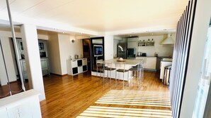 A modern kitchen with a central island, built-in appliances, and a dining area with a striped rug.