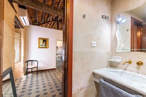 Un baño con lavamanos de mármol, una toalla y un espejo.