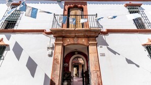 Un edificio con fachada blanca, techo de tejas rojas y un balcón con ropa tendida.