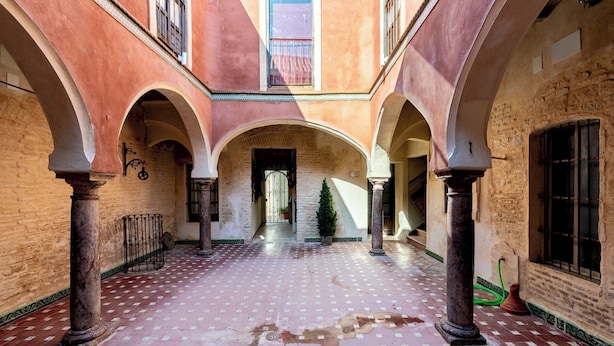 Un patio interior con arcos, suelo de baldosas y columnas.