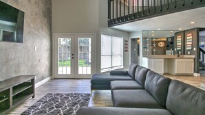 A modern living room with a grey sectional sofa, a patterned rug, and a built-in entertainment unit. - Spacious Family-Friendly 3BR Home w/ Yard Near Richmond & Rosenberg (Richmond)