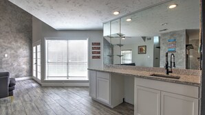 A modern kitchen with a large island, white cabinetry, and a large mirror above the sink. - Spacious Family-Friendly 3BR Home w/ Yard Near Richmond & Rosenberg (Richmond)